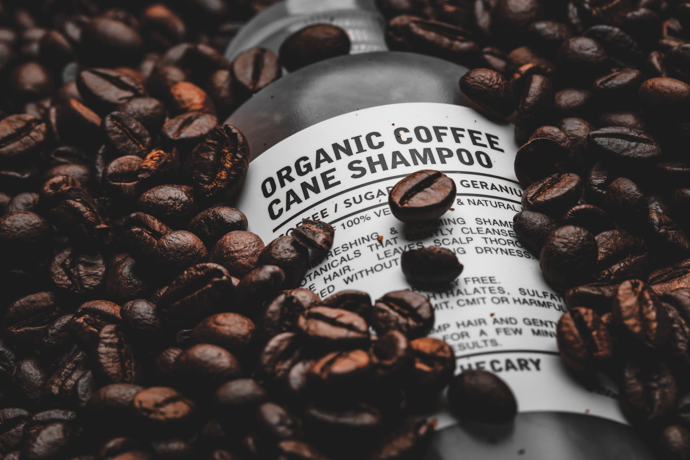 Coffee beans piled across the label of the Klarif organic coffee cane shampoo bottle